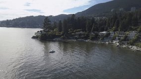 Aerial video of luxury homes near a beach with a beautiful view. Taken in West Vancouver, British Columbia, Canada, during a sunny summer day.