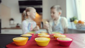 Portrait of two funny children enjoying muffins at modern kitchen