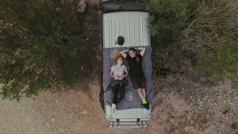 Top view on romantic couple on date, laying on roof of car or van, watch stars or sky in natural national park, secluded camping site in wilderness, concept relationship goals or millennials