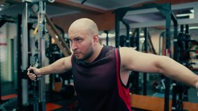 Man in gym doing pulls weight on cable machine