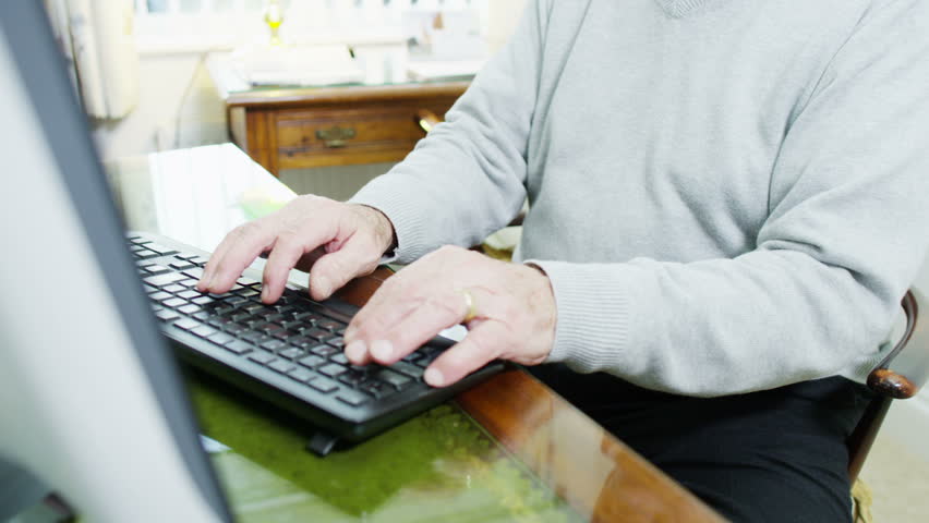 A senior gentleman is using his computer at home on a bright autumn day