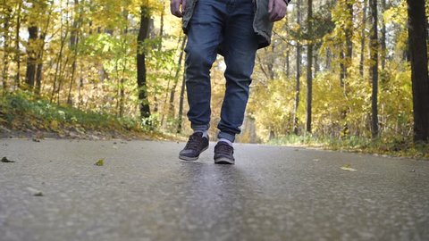 Man riding on a longboard skate on a road through a forest