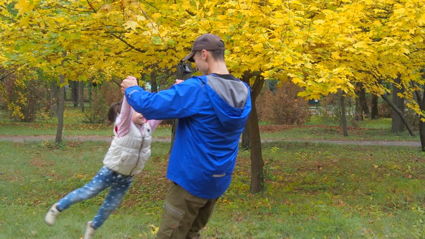 Father circling the child. Little girl is playing with dad on a plane in autumn park.