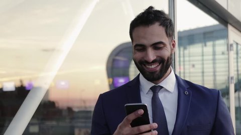 Close Up View of Stylish Bearded Businessman Using his Smartphone, smiles happily and texts back. Elegant Look, Bachelor. Modern Culture, Contemporary Communication.