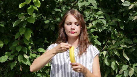 Beautiful girl eating a ripe banana