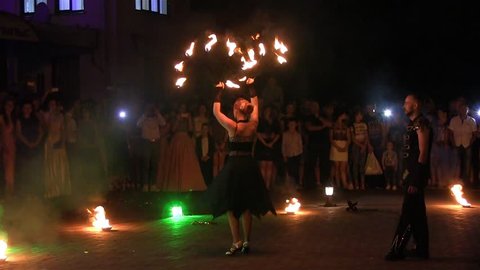 KIEV, UKRAINE - SEPTEMBER 2017 Amazing fireshow by young woman and man on a street in a night city..