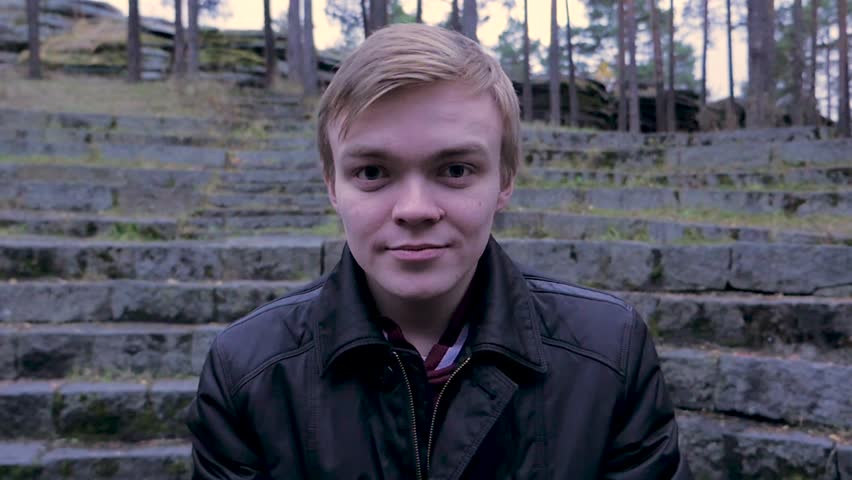 Close up of a handsome young man standing outdoors with jacket. Young man stands in a Park in autumn