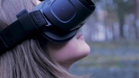 Beautiful woman with virtual reality in outdoor park. VR headset glasses device. Young woman in a VR glasses in the Park. Close-up