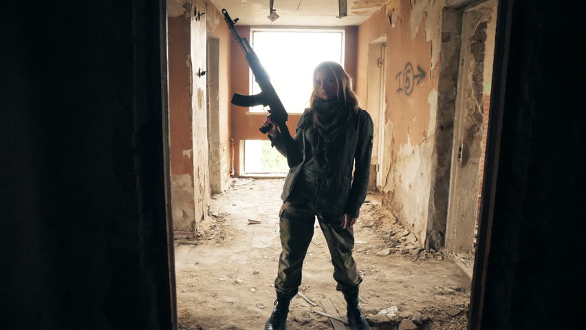 woman holding a automatic rifle and posting in abandoned building