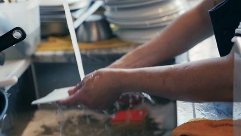 Woman washing dishes in the kitchen. Close up of woman hand. Housewife clean dishes. Modern restaurant.