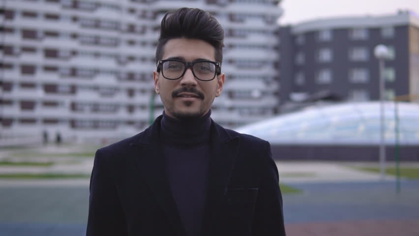 Portrait of young attractive businessman in glasses and looking at the camera. Man smiling and making thumbs up, slow motion.