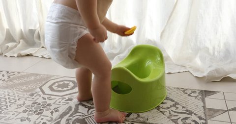 Baby and chamber-pot. Toddler play from the pot in interiors