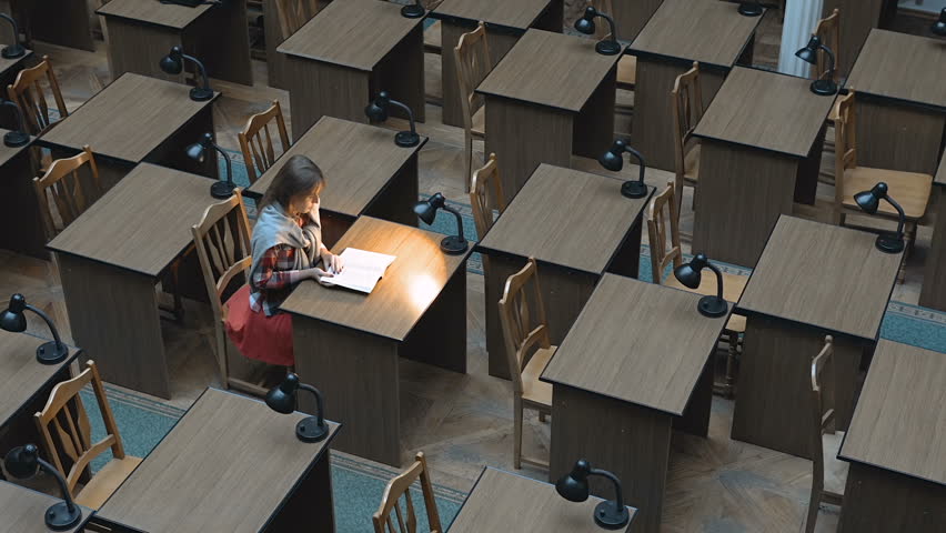 Student reading book in a library hall with tables and lamps, top view  Royalty-Free Stock Footage #32137231