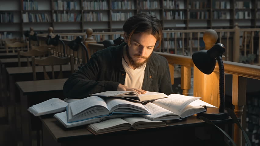 Bored student use books for studying to exams before bookshelves in evening time in the library Royalty-Free Stock Footage #32137237