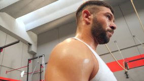 Sweaty male athlete breathing and walking at cross fitness gym in slow motion