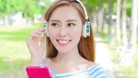 woman smile happily and use phone listen music in the park