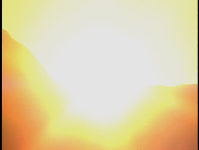 Zoom out from sun to reveal alpine lake with reflection