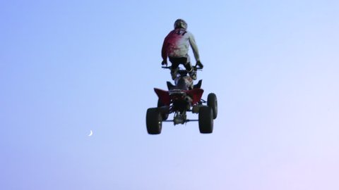 freestyle atv riders doing back to back cliffhangers trick with moon for background