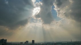 4K Time lapse video of rain clouds moving over bright sun light making many sun beams over a town.