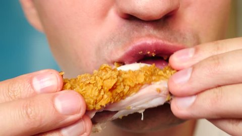 close-up, man eats, fast food, chicken nuggets, wings and french fries.