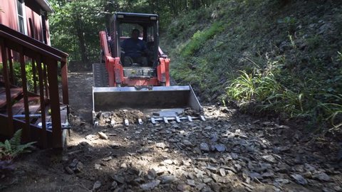 Kubota track skid steer smooths out the stones and dirt excavating for landscaping and