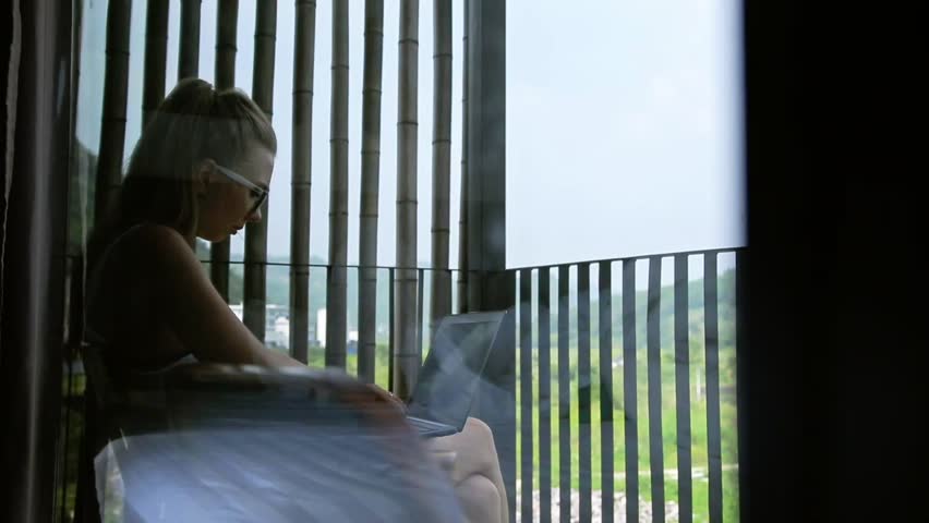 Young woman surfing on internet outside the house on the terrace with a view over Guiling mountain landscape in Yangshuo County,China.