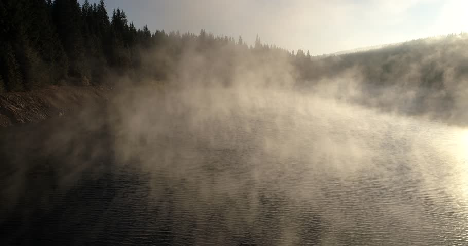 flight over a misty mountain lake in the morning golden light