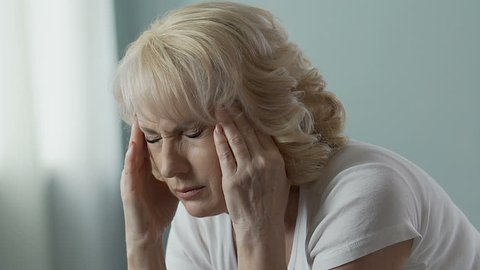 Aged woman rubbing temples intensely, splitting headache, problems with health