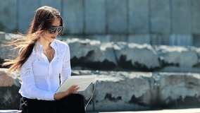 Businesswoman speaks via tablet pc. Young attractive woman in glasses with white tablet computer in hands communicates through video chat