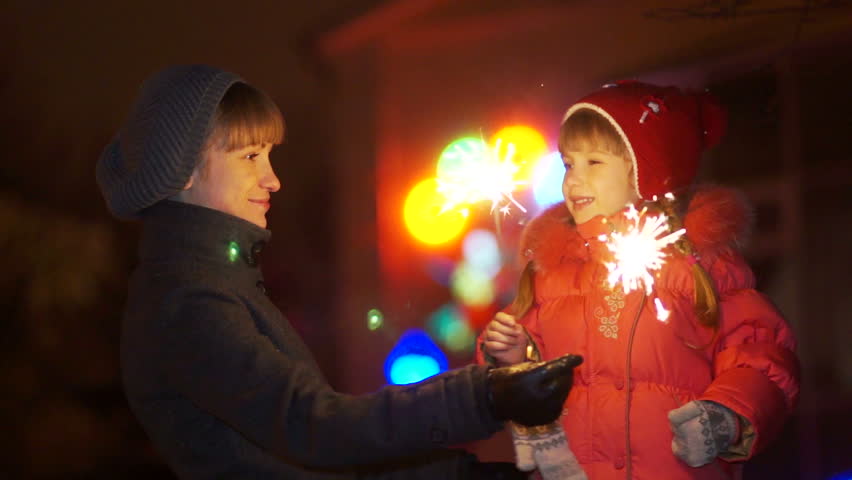Mother and daughter with sparklers at night