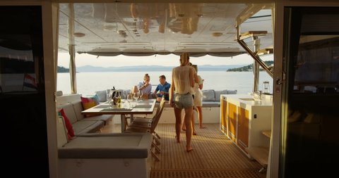 Group of Successful Young People Join Others in the Stern of the Yacht with Cocktails. In the Background Calm Sea and Islands. Shot on RED Epic 4K UHD Camera.