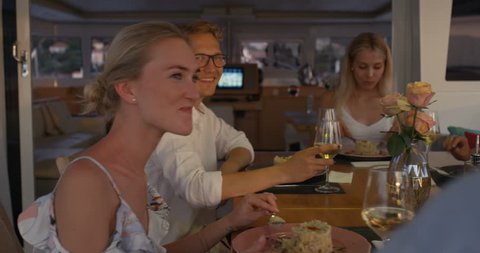 Group of Successful Young People Eat Deserts on Yacht. It's Evening, Sea is Calm and Islands are Visible on the Horizon. Shot on RED Epic 4K UHD Camera.