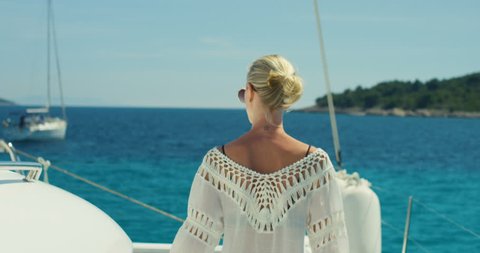 Following Shot of a Beautiful Woman Walking on the Yacht's Deck. Sun Shines, Islands and Azure Sea in the Background. Shot on RED Epic 4K UHD Camera.