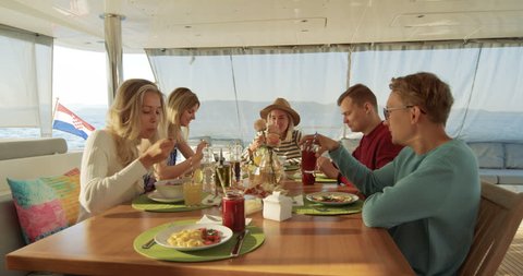 Group of Young Beautiful People Eating Healthy Breakfast on a Yacht, They're Talking. They Have Various Vegetables and Smoothies on the Table. Sea is in the Background. Shot on RED Epic 4K UHD Camera.