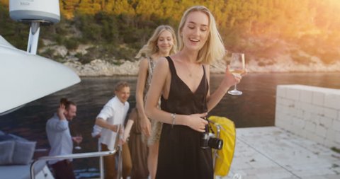 Company of Young Girls and Boys in Fashionable Clothes Leave Yacht To Party. Beautiful Seaside View and Happy People. Shot on RED Epic 4K UHD Camera.