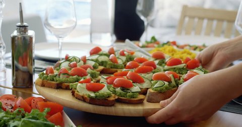 Waiter Serves Beautiful Organic Avocado Sandwiches/ Bruschetta on a Wooden Tray, Table Furnished in Mediterranean Food: Seasonal Vegetables, Olive Oil. Shot on RED Epic 4K UHD Camera.