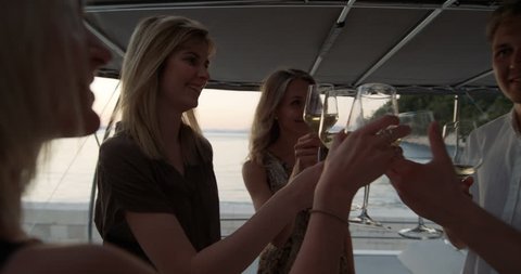 Group of Successful Young People Clink Cocktail Glasses in Celebration while Vacationing on a Yacht.Shot on RED Epic 4K UHD Camera.