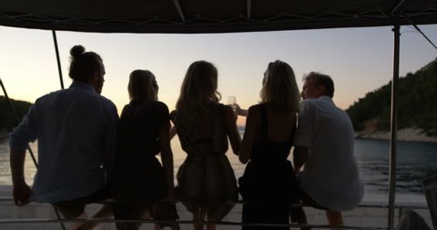 Group of Successful Young People Clink Cocktail Glasses in Celebration while Vacationing on a Yacht. Shot on RED Epic 4K UHD Camera.