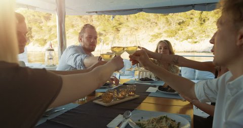 Company of Young People on a Yacht, They Clink Glasses in Celebration. Table Served with Steamed Mussels. Beautiful Seaside View. Shot on RED Epic 4K UHD Camera.