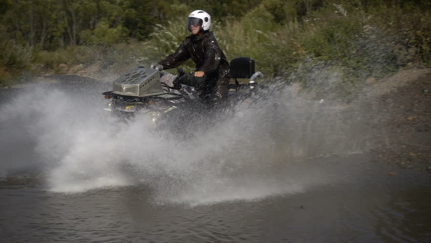Quad crossing a river. youngman traveling on a mountain river with splashes. ATV for off-road. Super slo-mo water splashing. summer. good weather