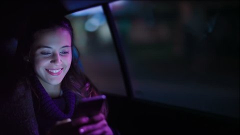 Close up of attractive woman in a car using a mobile phone. She is texting, checking mails, chats or the news online.