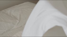 Woman flapping bed sheets in 92 fps slow motion as she turns around and smiles at the camera