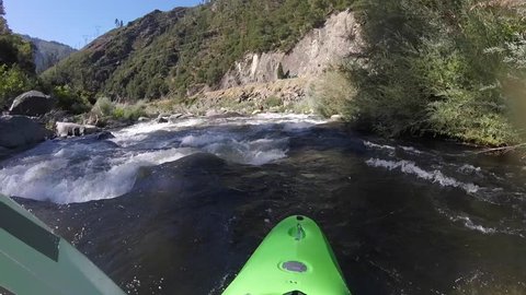 A white water kayaker paddling some bumpy rapids. POV