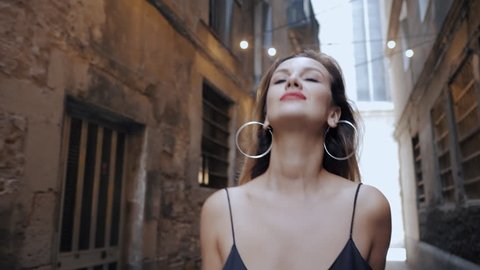Gorgeous blonde alluring woman in sexy black dress and red lips walking in gothic quarter of Barcelona. Natural beauty, female portrait, seductive look. Being self-confident. 4k
