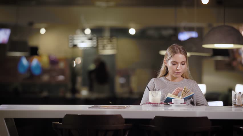 Sensual young model posing romantically at counter in modern cafe