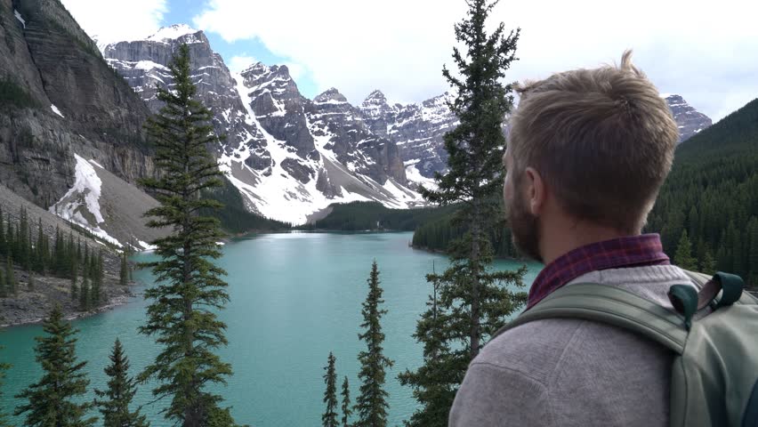 Young male hiking in canada stops by the lake Moraine to frame the beautiful landscape with hands. Travel beginnings and building a future concept