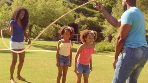 Family skipping with rope in park