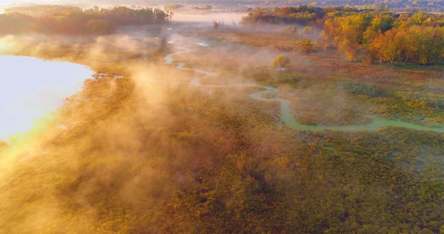 Aerial view of breathtaking foggy wilderness at dawn, with winding river, Autumn colors.