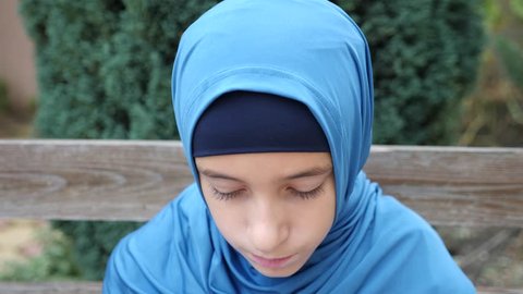 portrait of a modest girl, a Muslim wearing a hijab looks at the camera, 4k, slow-motion. copy space