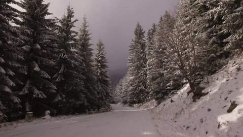 Low angle driving POV curve on snowy country road in mountains